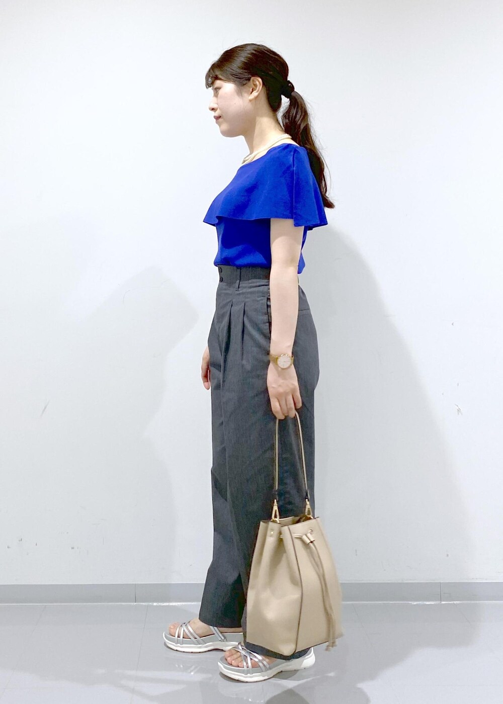 ベージュ系のショルダーバッグ、シルバー系のサンダル、グレー系のチノパンツを着用したレディースの夏コーディネートの5枚目の写真