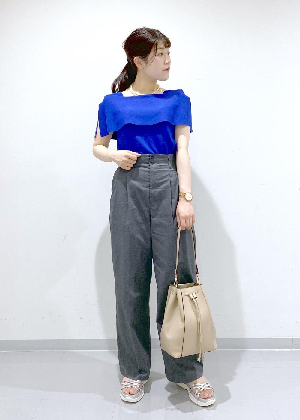 ベージュ系のショルダーバッグ、シルバー系のサンダル、グレー系のチノパンツを着用したレディースの夏コーディネートの4枚目の写真