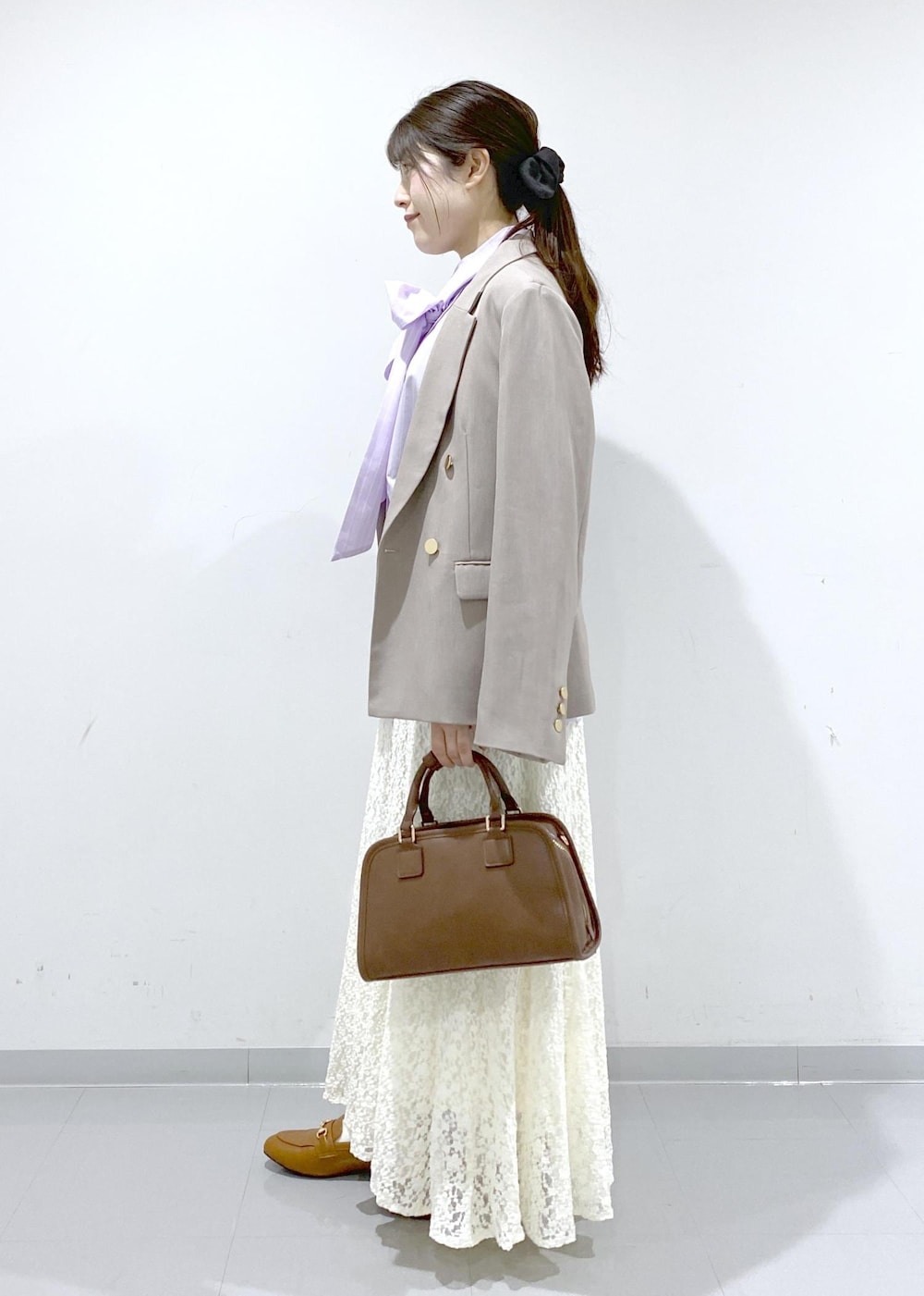 イエロー系のローファー、ブラウン系のボストンバッグ、ベージュ系のテーラードジャケットを着用したレディースの冬コーディネートの4枚目の写真