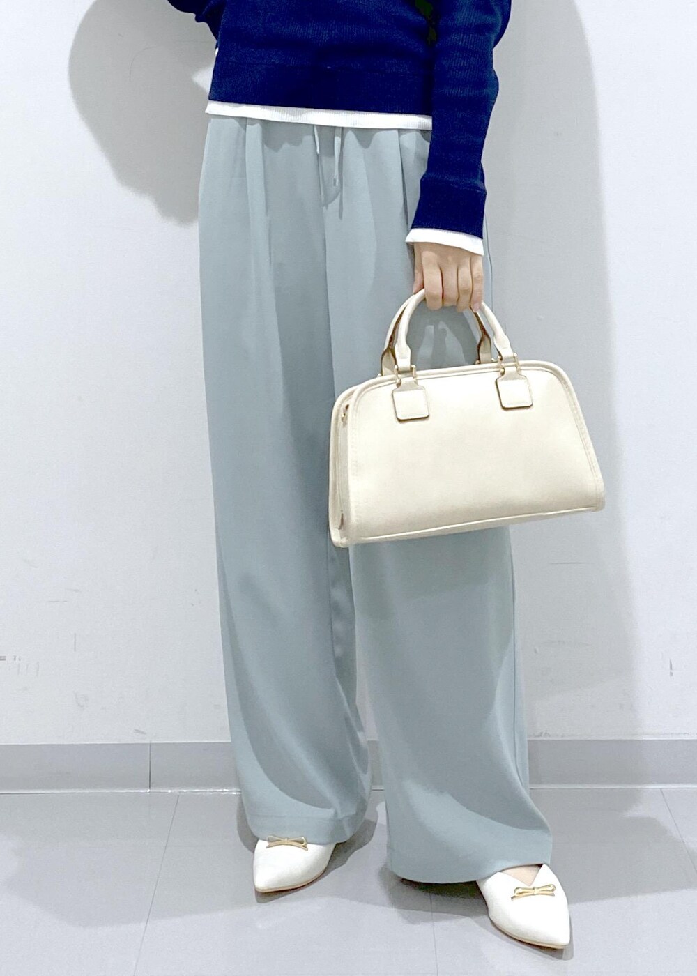 ホワイト系のボストンバッグ、ホワイト系のパンプス、ブルー系のニット/セーターを着用したレディースの冬コーディネートの10枚目の写真