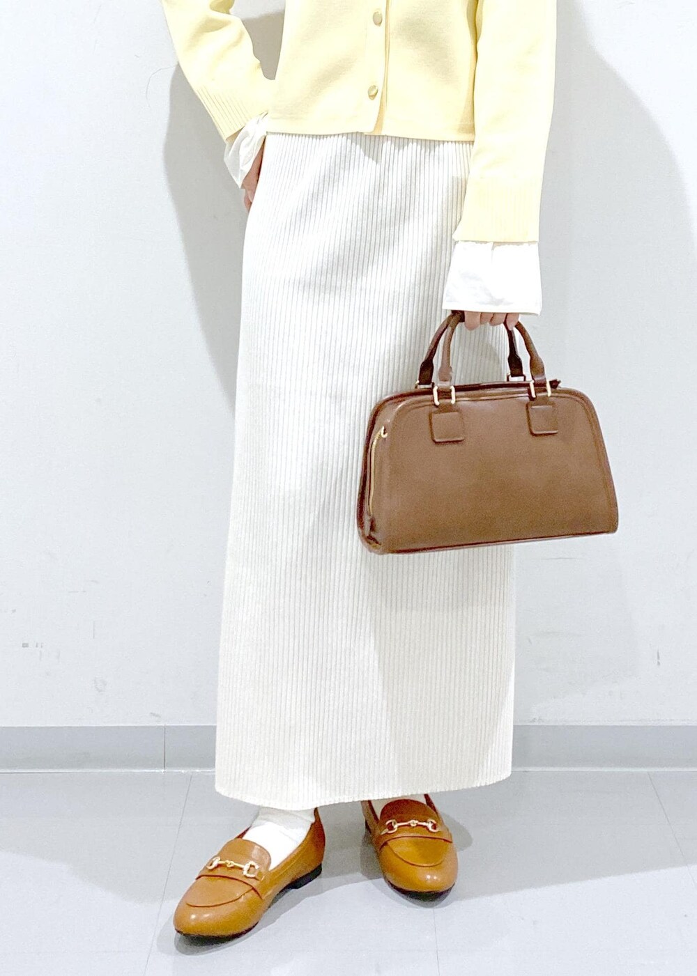 イエロー系のローファー、ブラウン系のボストンバッグ、ホワイト系のスカートを着用したレディースの冬コーディネートの10枚目の写真