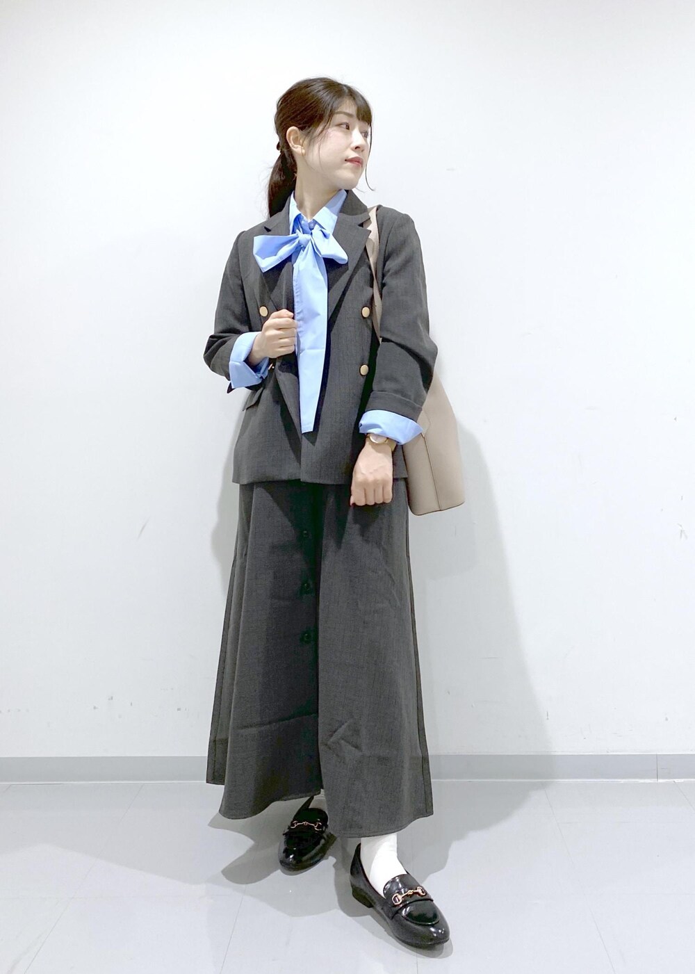 ベージュ系のショルダーバッグ、ブラック系のジャンパースカート、ブラック系のテーラードジャケットを着用したレディースの秋コーディネートの8枚目の写真