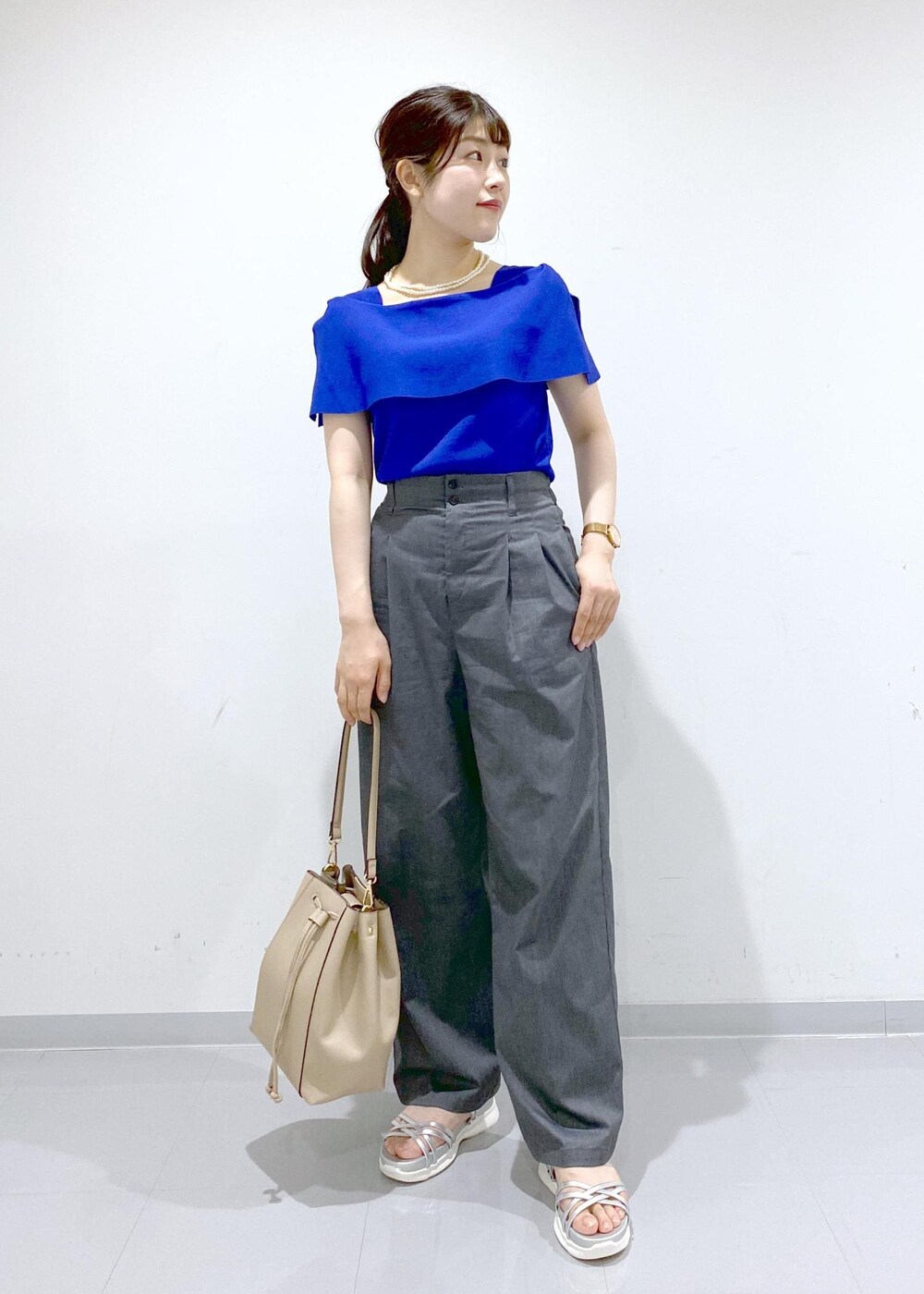 ベージュ系のショルダーバッグ、シルバー系のサンダル、グレー系のチノパンツを着用したレディースの夏コーディネートの2枚目の写真