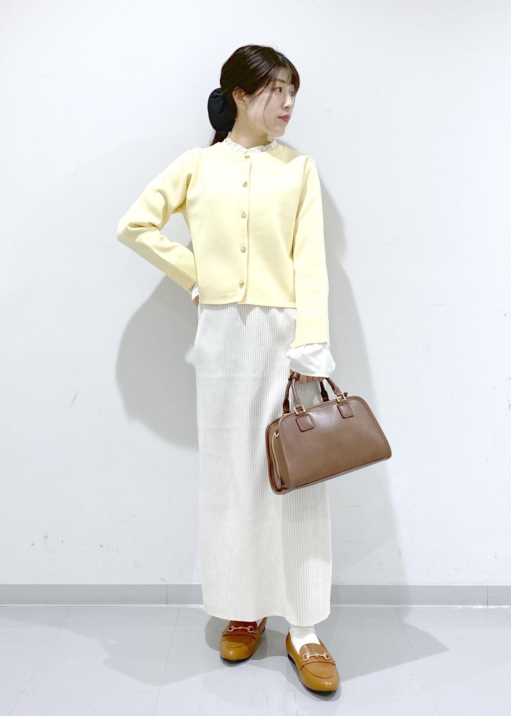 イエロー系のローファー、ブラウン系のボストンバッグ、ホワイト系のスカートを着用したレディースの冬コーディネートの7枚目の写真