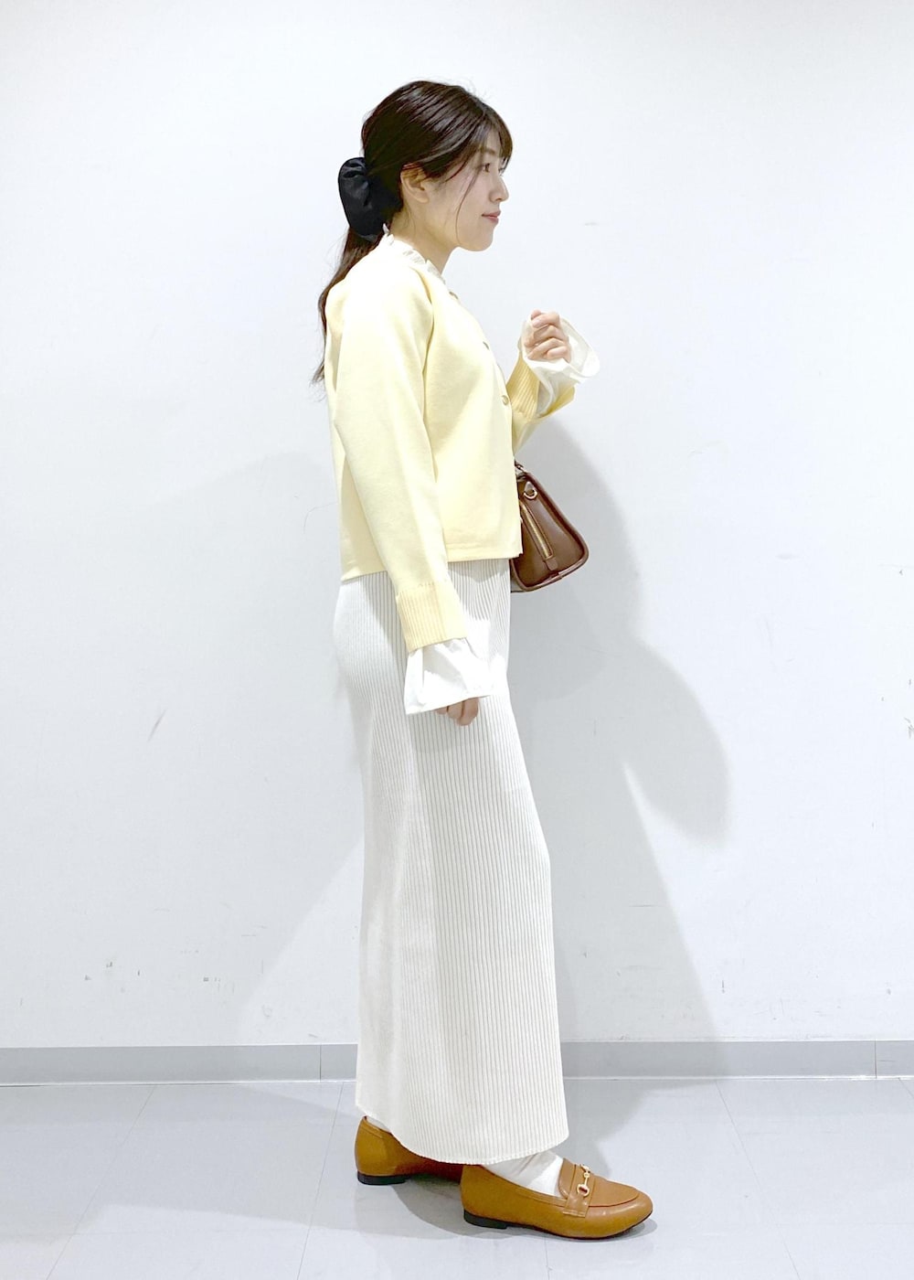 イエロー系のローファー、ブラウン系のボストンバッグ、ホワイト系のスカートを着用したレディースの冬コーディネートの6枚目の写真