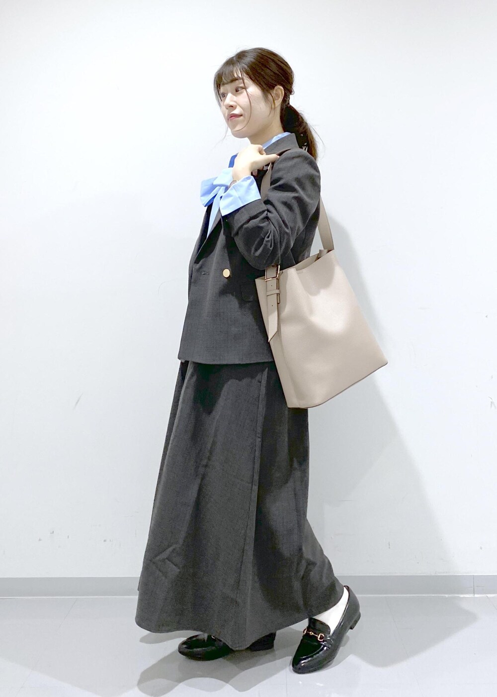 ベージュ系のショルダーバッグ、ブラック系のジャンパースカート、ブラック系のテーラードジャケットを着用したレディースの秋コーディネートの4枚目の写真