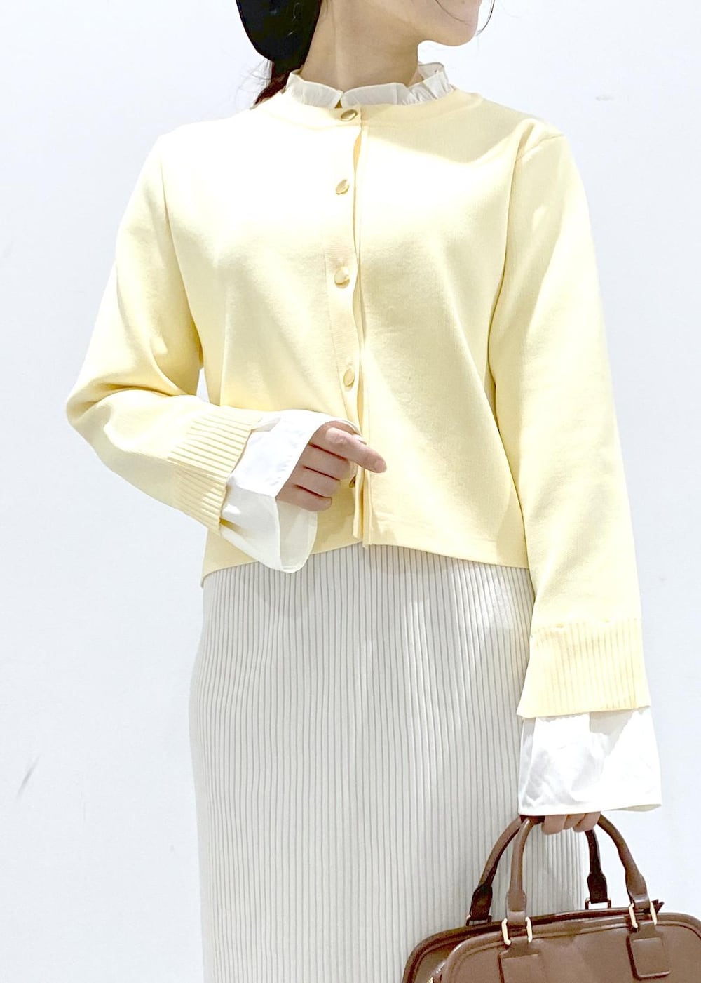 イエロー系のローファー、ブラウン系のボストンバッグ、ホワイト系のスカートを着用したレディースの冬コーディネートの9枚目の写真