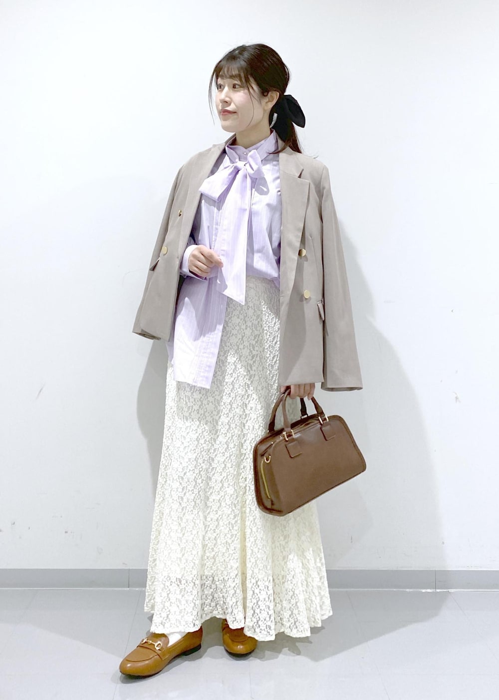 イエロー系のローファー、ブラウン系のボストンバッグ、ベージュ系のテーラードジャケットを着用したレディースの冬コーディネートの3枚目の写真