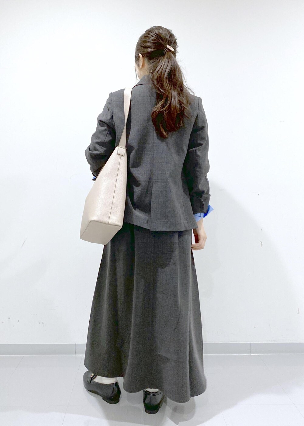 ベージュ系のショルダーバッグ、ブラック系のジャンパースカート、ブラック系のテーラードジャケットを着用したレディースの秋コーディネートの5枚目の写真