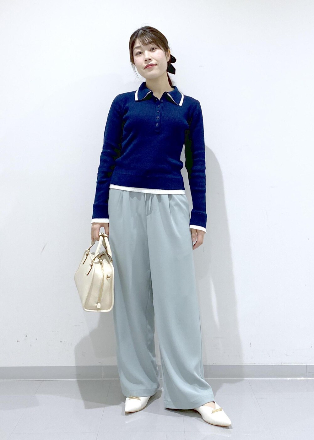 ホワイト系のボストンバッグ、ホワイト系のパンプス、ブルー系のニット/セーターを着用したレディースの冬コーディネートの7枚目の写真