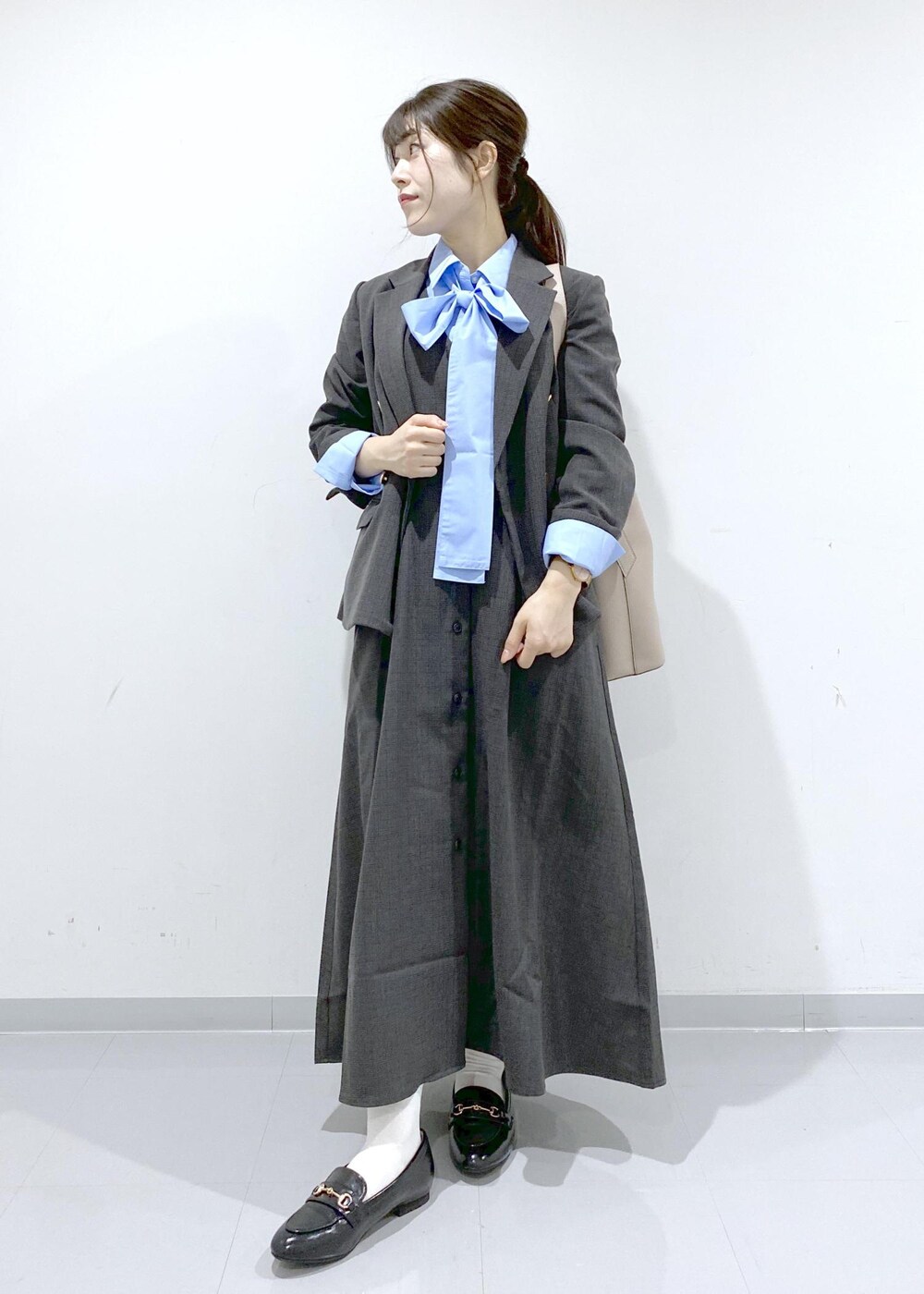 ベージュ系のショルダーバッグ、ブラック系のジャンパースカート、ブラック系のテーラードジャケットを着用したレディースの秋コーディネートの2枚目の写真