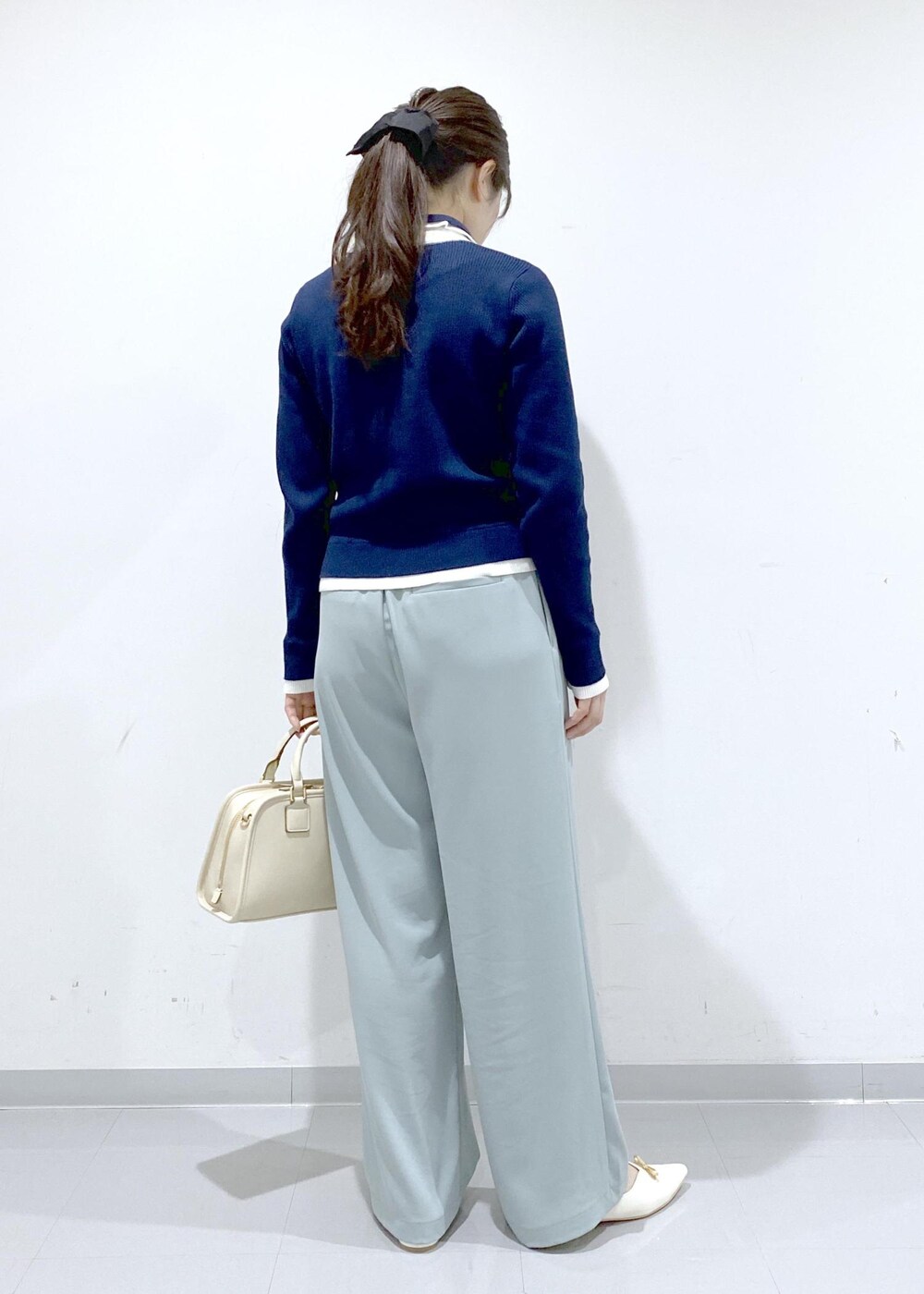 ホワイト系のボストンバッグ、ホワイト系のパンプス、ブルー系のニット/セーターを着用したレディースの冬コーディネートの5枚目の写真