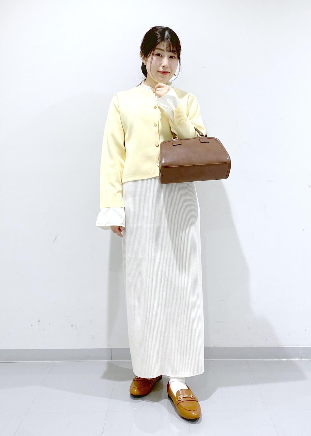 イエロー系のローファー、ブラウン系のボストンバッグ、ホワイト系のスカートを着用したレディースの冬コーディネートの8枚目の写真