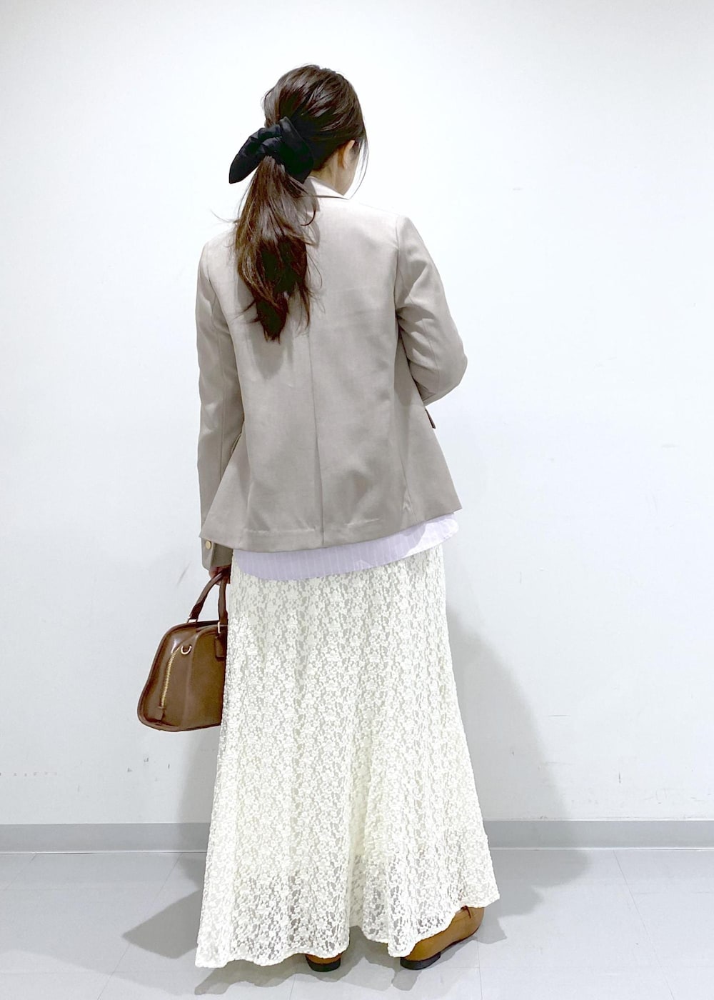 イエロー系のローファー、ブラウン系のボストンバッグ、ベージュ系のテーラードジャケットを着用したレディースの冬コーディネートの5枚目の写真