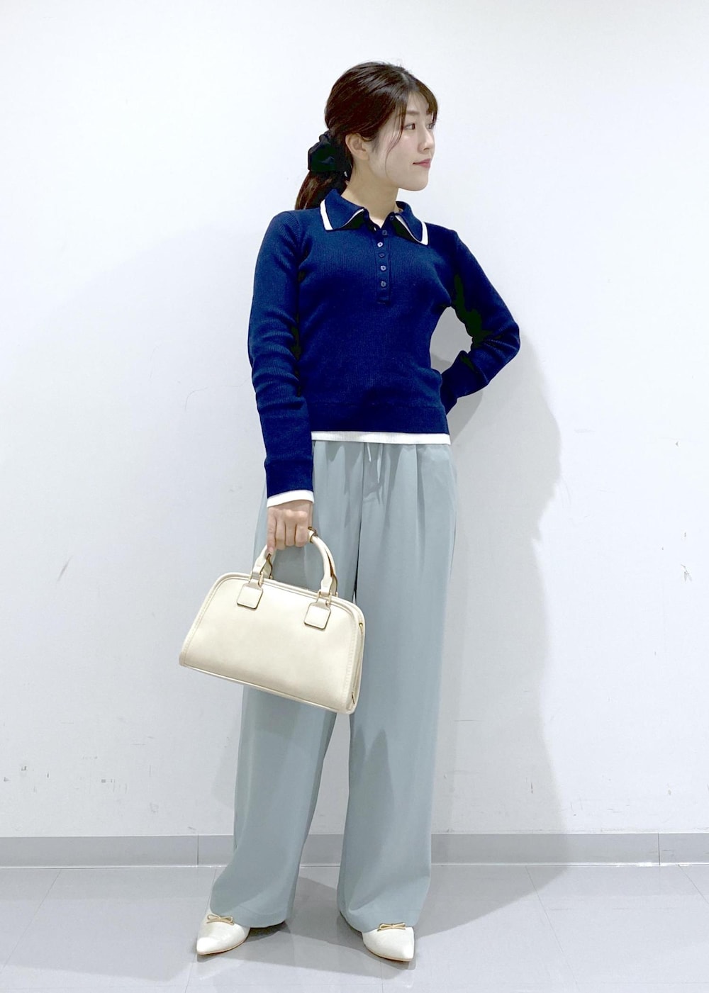ホワイト系のボストンバッグ、ホワイト系のパンプス、ブルー系のニット/セーターを着用したレディースの冬コーディネートの3枚目の写真