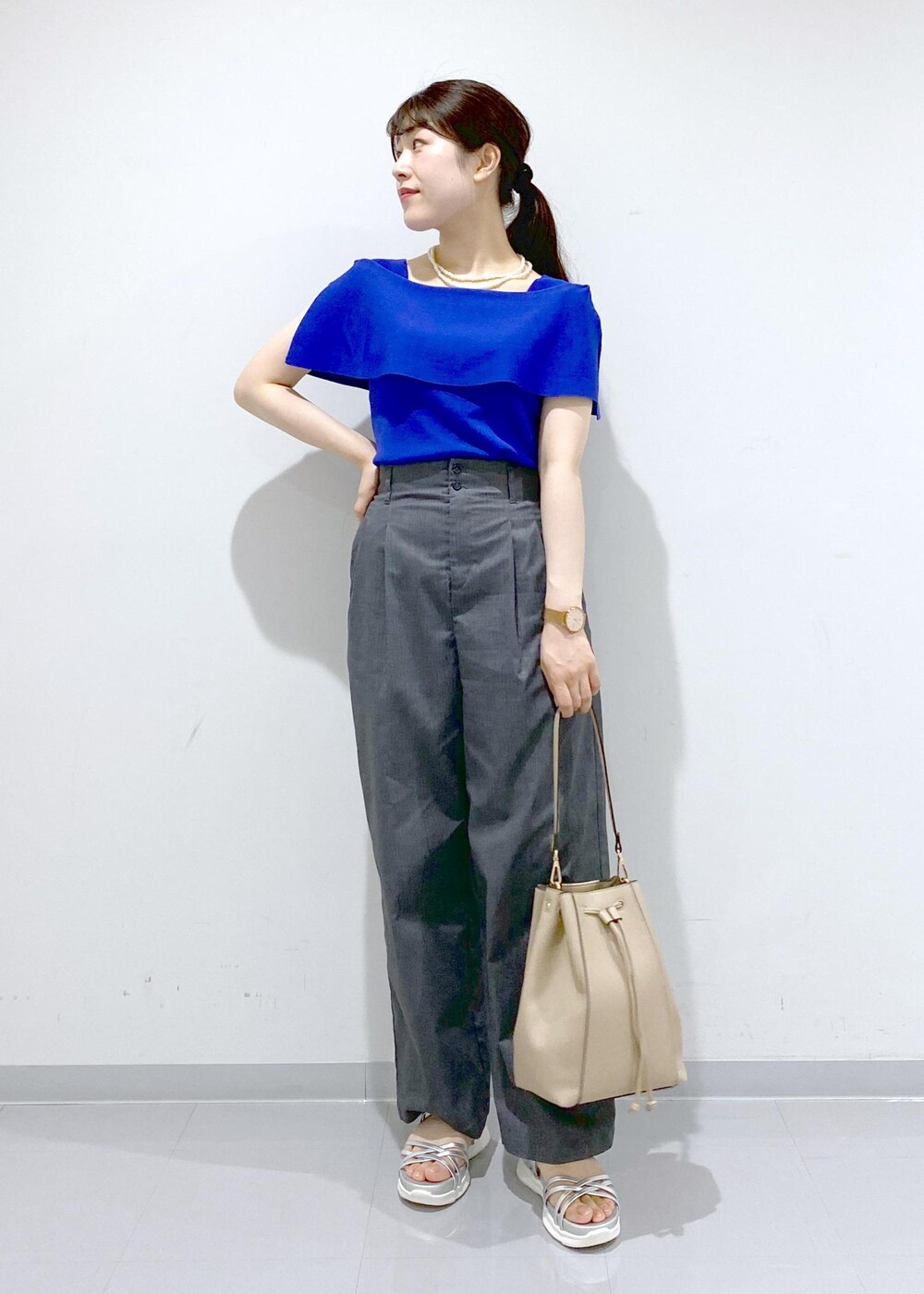 ベージュ系のショルダーバッグ、シルバー系のサンダル、グレー系のチノパンツを着用したレディースの夏コーディネートの3枚目の写真