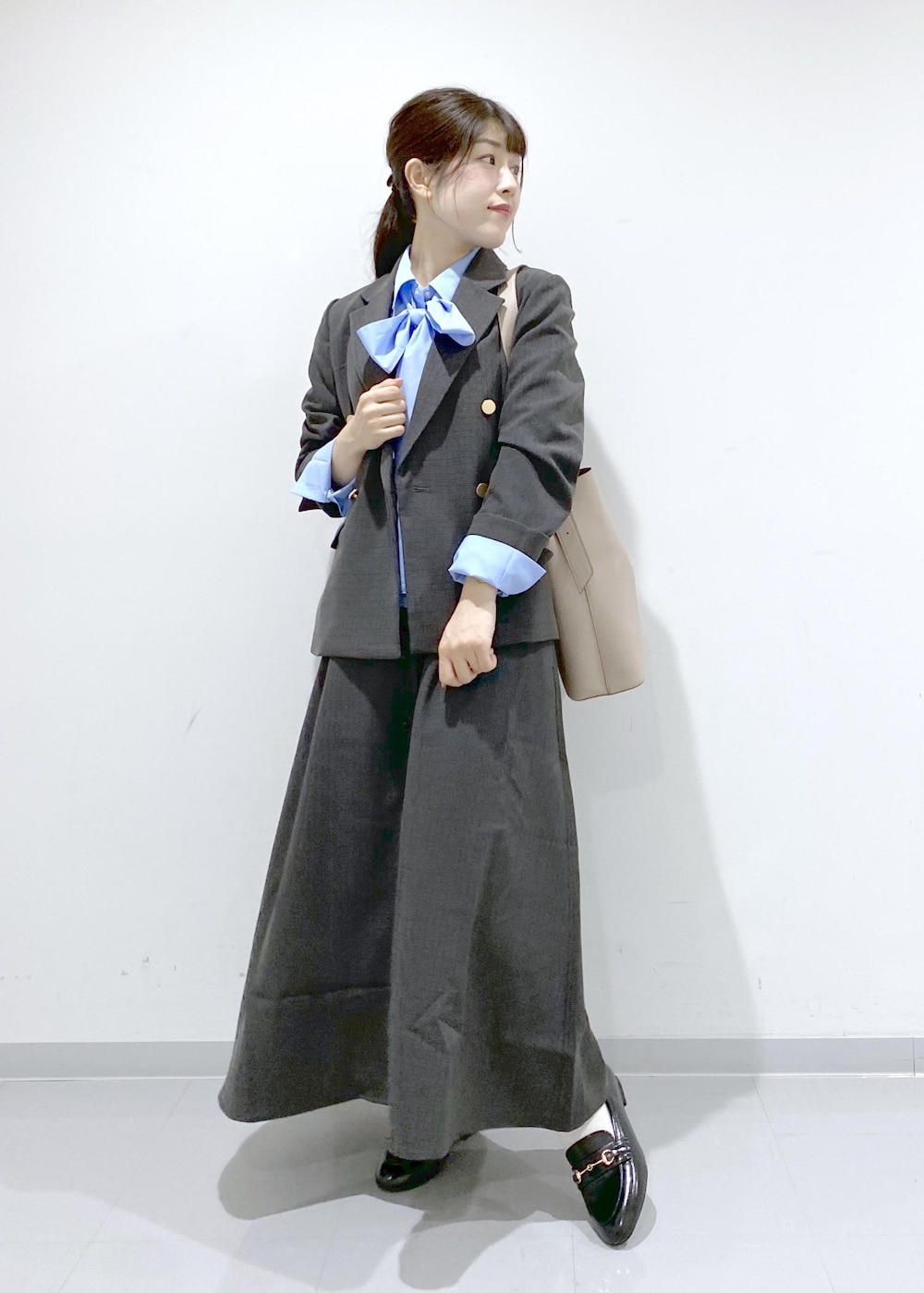 ベージュ系のショルダーバッグ、ブラック系のジャンパースカート、ブラック系のテーラードジャケットを着用したレディースの秋コーディネートの3枚目の写真