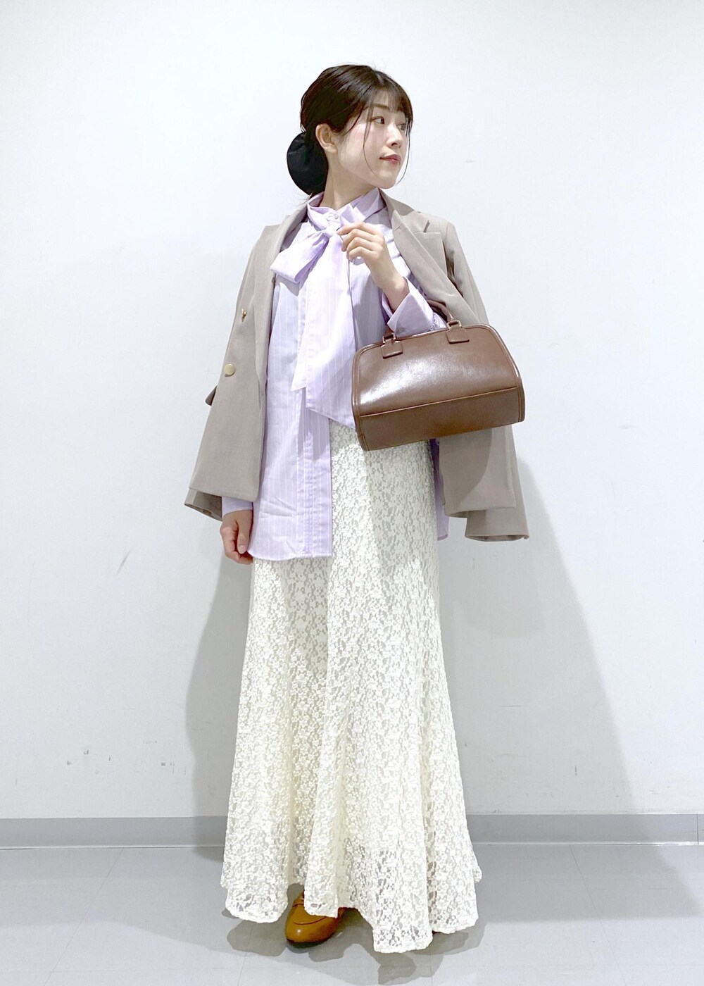 イエロー系のローファー、ブラウン系のボストンバッグ、ベージュ系のテーラードジャケットを着用したレディースの冬コーディネートの2枚目の写真