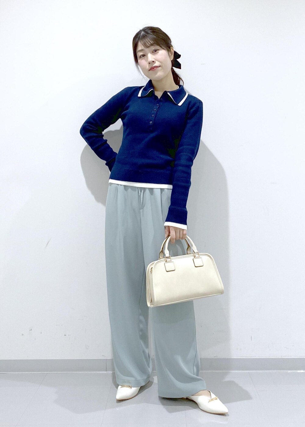 ホワイト系のボストンバッグ、ホワイト系のパンプス、ブルー系のニット/セーターを着用したレディースの冬コーディネートの2枚目の写真