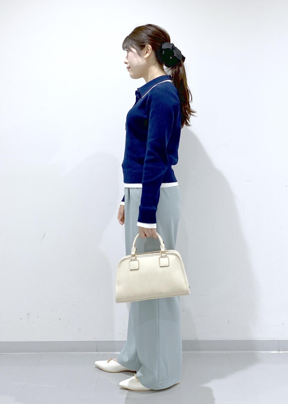 ホワイト系のボストンバッグ、ホワイト系のパンプス、ブルー系のニット/セーターを着用したレディースの冬コーディネートの4枚目の写真