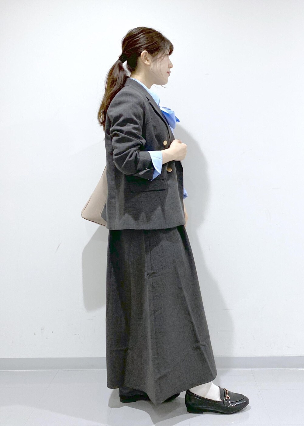 ベージュ系のショルダーバッグ、ブラック系のジャンパースカート、ブラック系のテーラードジャケットを着用したレディースの秋コーディネートの6枚目の写真