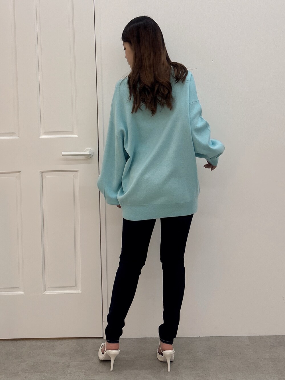 ブルー系のニット/セーター、ブルー系のデニムパンツ、ホワイト系のパンプスを着用したレディースの冬コーディネートの3枚目の写真