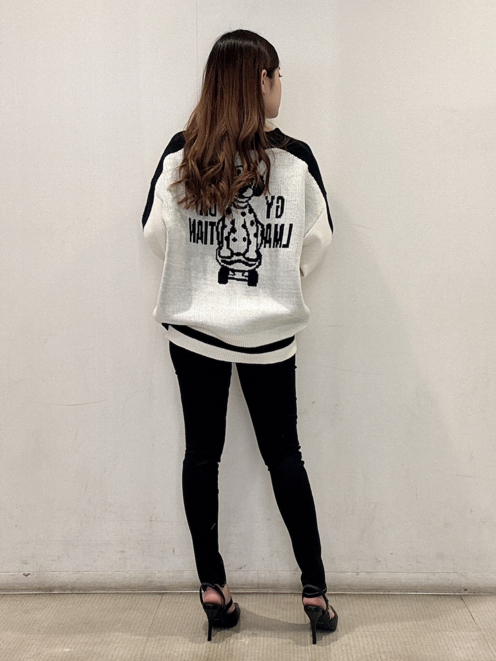 ホワイト系のニット/セーター、ブラック系のデニムパンツ、ブラック系のパンプスを着用したレディースの春コーディネートの4枚目の写真