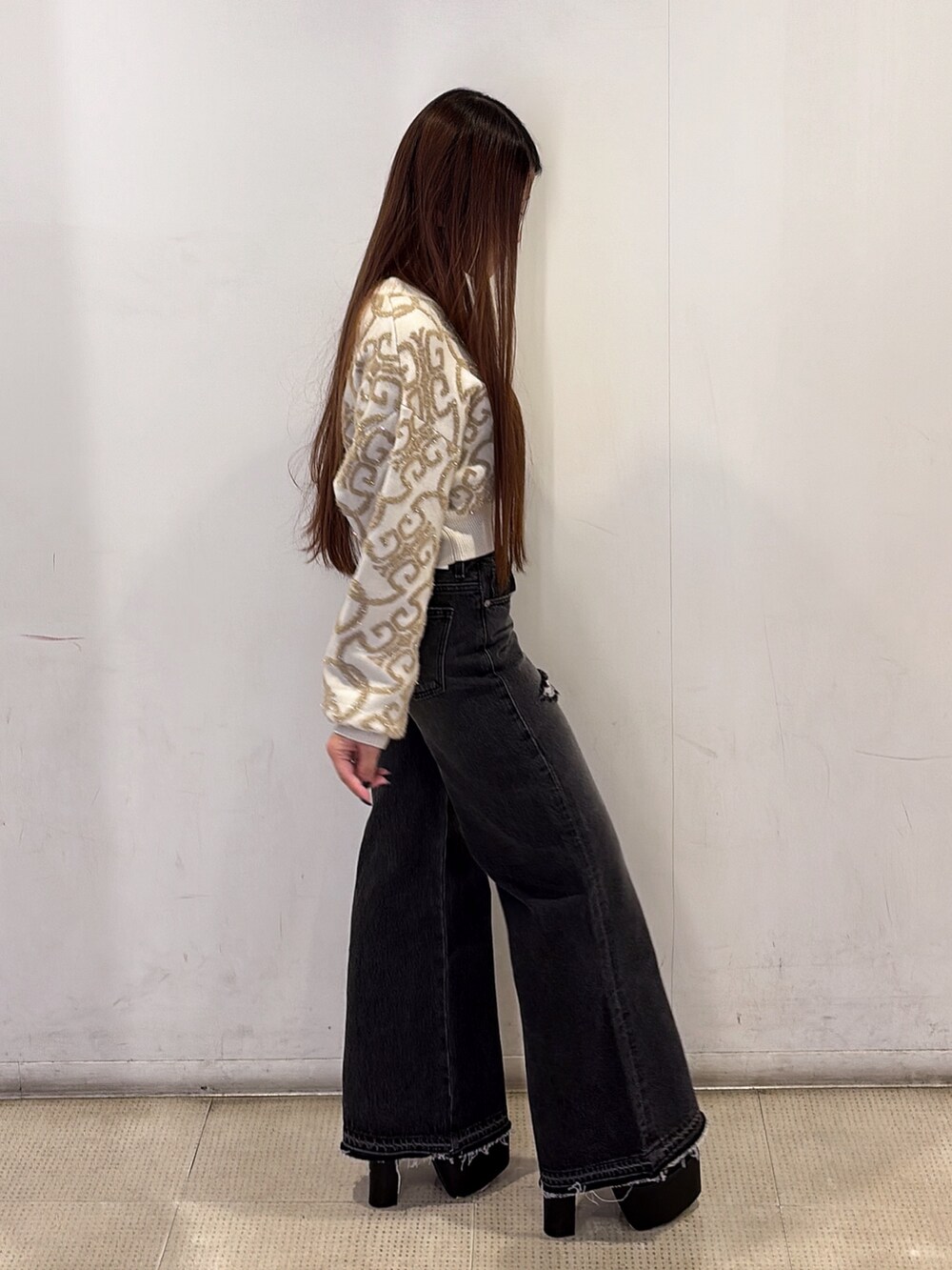 ホワイト系のニット/セーター、ブラック系のデニムパンツ、ブラック系のブーツを着用したレディースの秋コーディネートの2枚目の写真