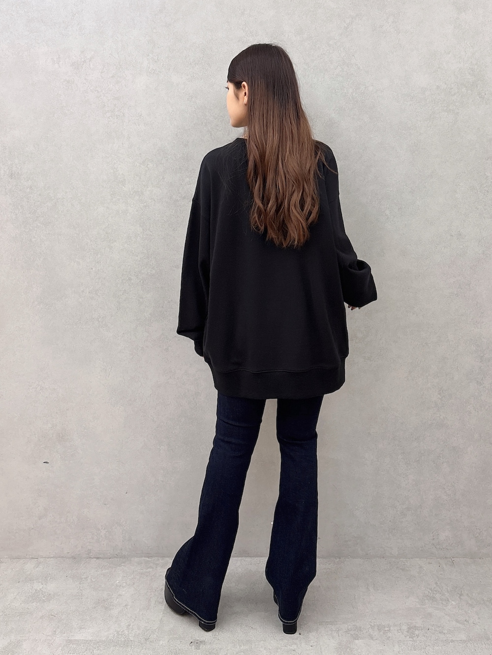 ブラック系のスウェット、ブルー系のデニムパンツ、ブラック系のサンダルを着用したレディースの夏コーディネートの3枚目の写真