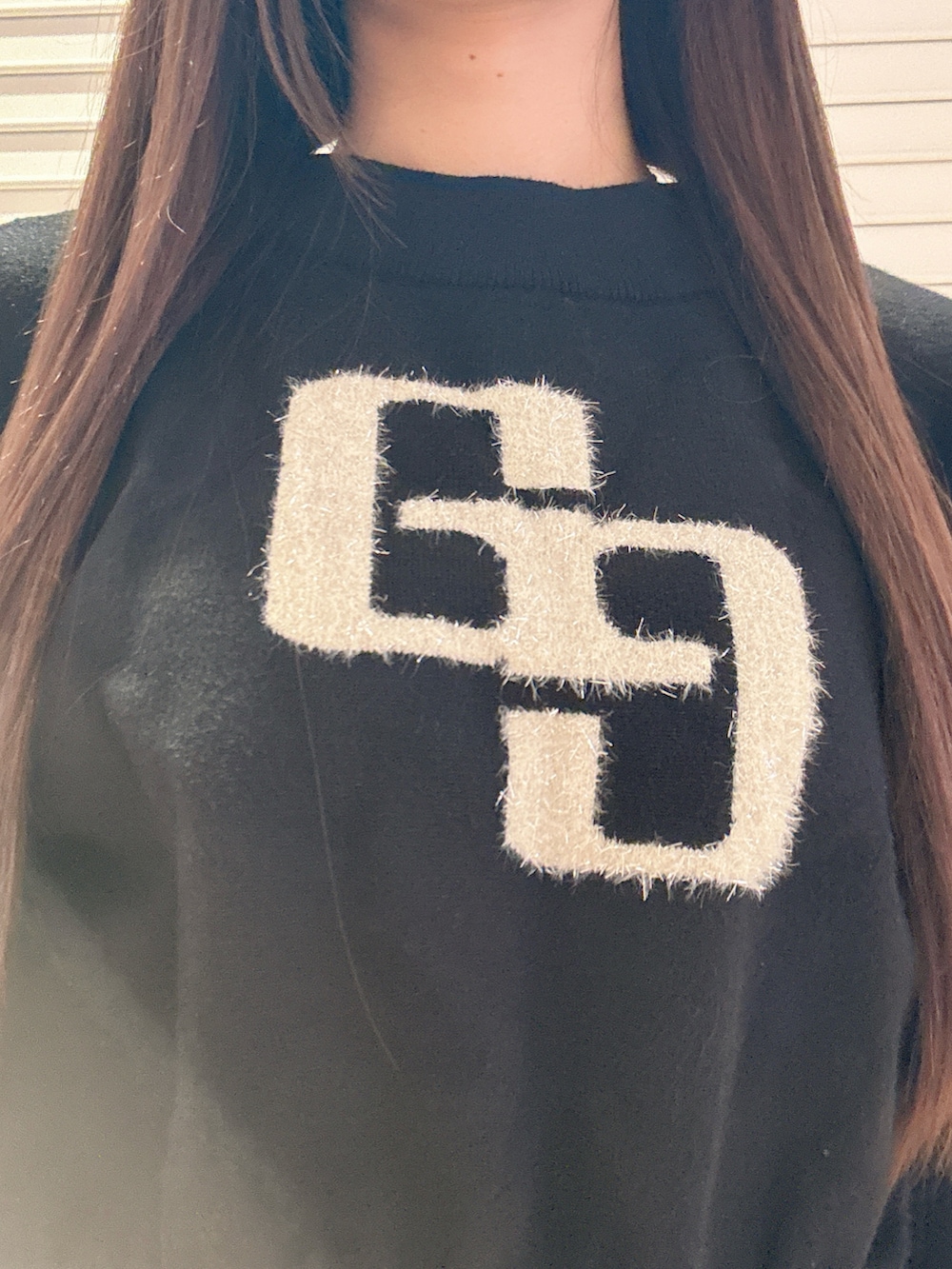 ブラック系のニット/セーター、ブルー系のデニムパンツ、ブラック系のブーツを着用したレディースの秋コーディネートの6枚目の写真