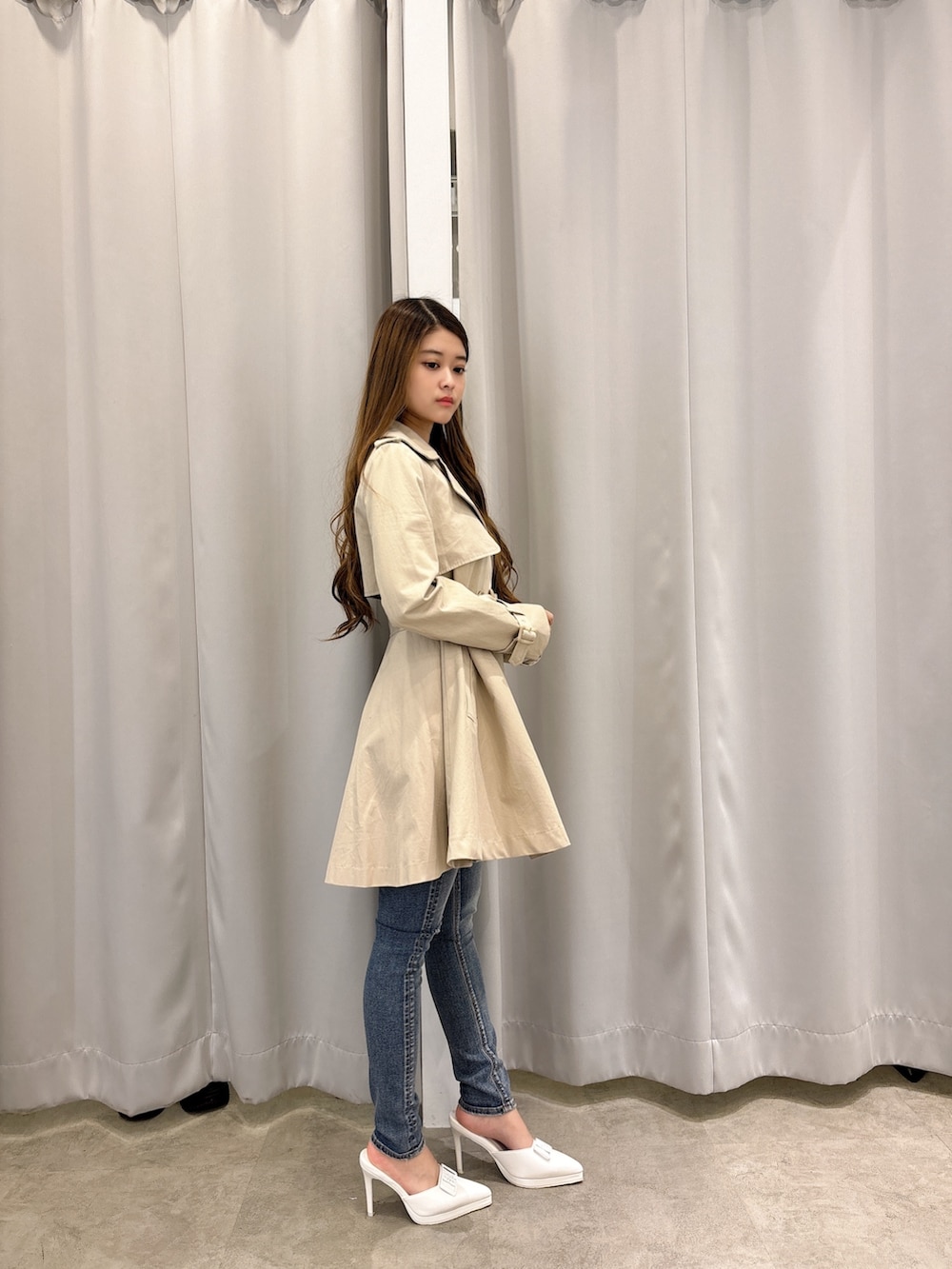 ベージュ系のトレンチコート、ブルー系のデニムパンツ、ホワイト系のパンプスを着用したレディースの春コーディネートの2枚目の写真