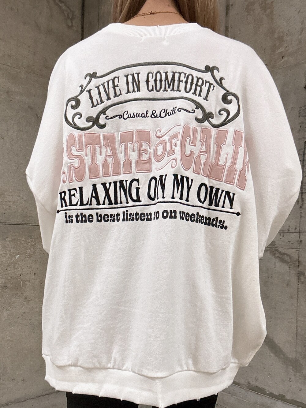 ホワイト系のスウェット、ブラック系のデニムパンツ、ブラック系のブーツを着用したレディースの秋コーディネートの5枚目の写真