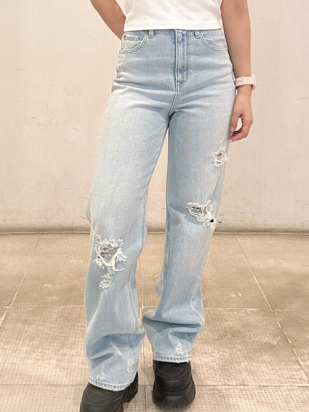 ブラック系のスニーカー、ホワイト系のタンクトップ、ブルー系のデニムパンツを着用したレディースの春コーディネートの6枚目の写真