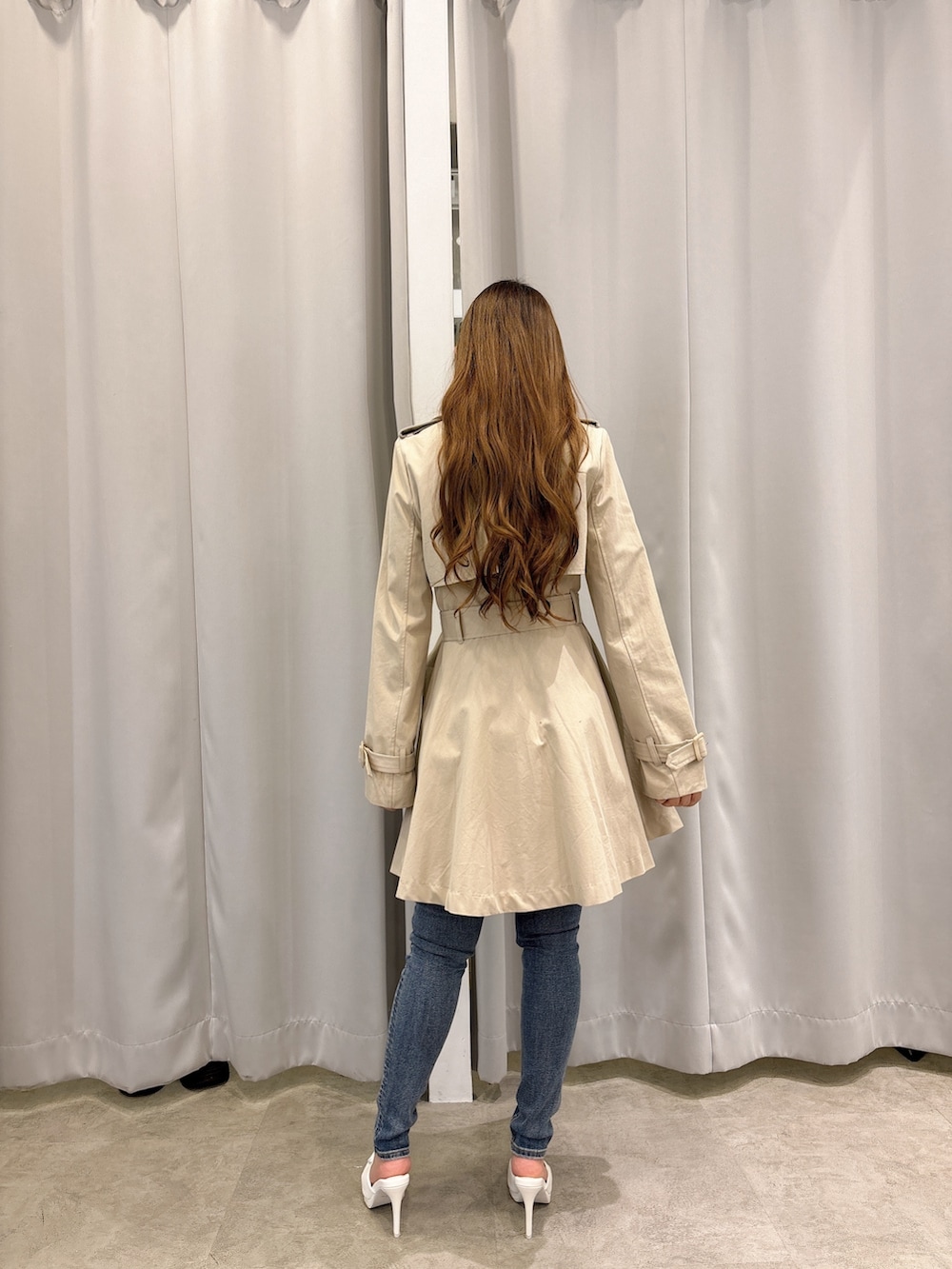 ベージュ系のトレンチコート、ブルー系のデニムパンツ、ホワイト系のパンプスを着用したレディースの春コーディネートの3枚目の写真