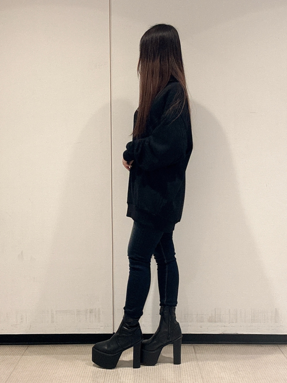 ブラック系のパーカー、ブルー系のデニムパンツ、ブラック系のブーツを着用したレディースの秋コーディネートの2枚目の写真