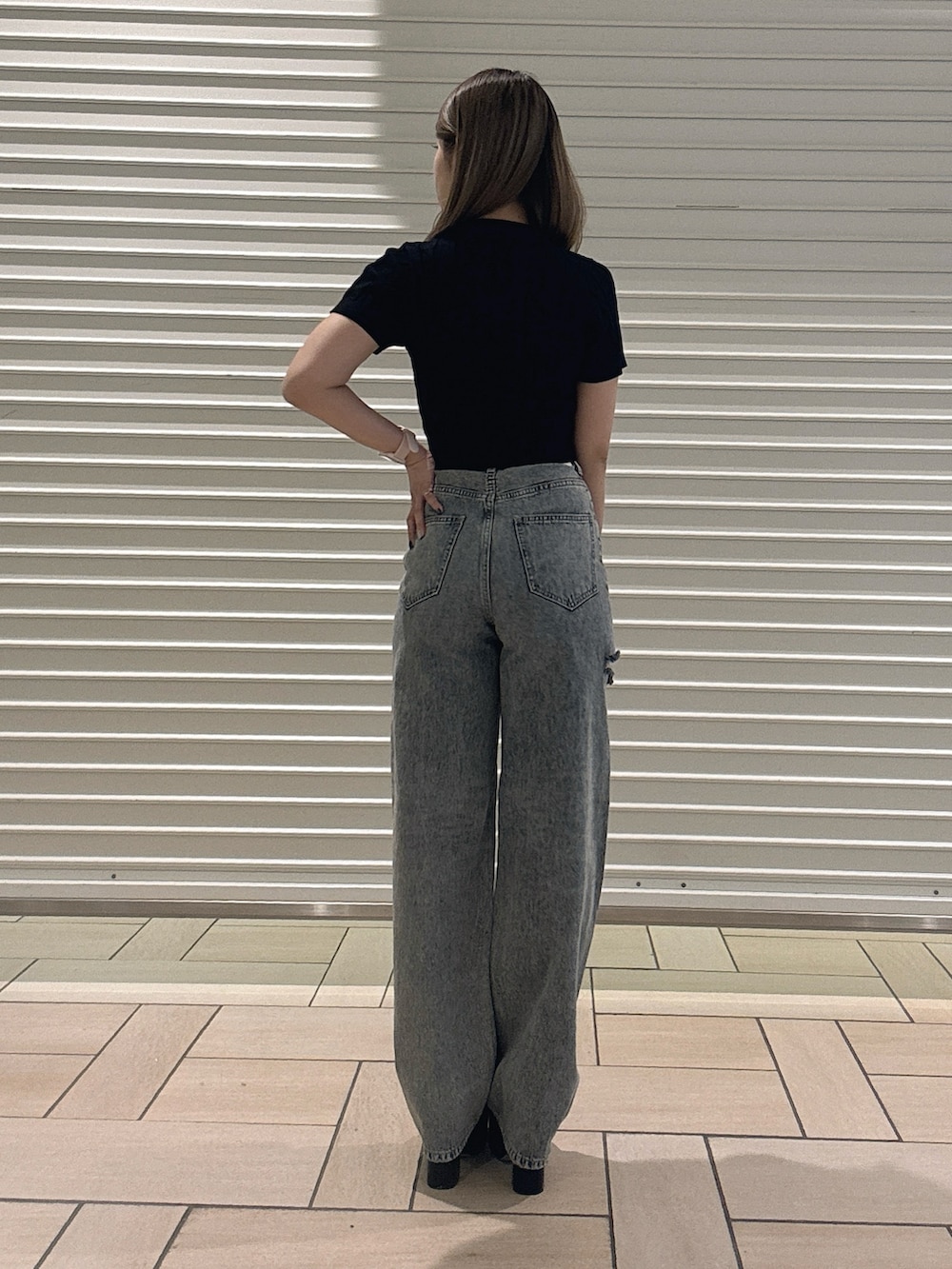 ブラック系のTシャツ/カットソー、ブルー系のデニムパンツ、ブラック系のサンダルを着用したレディースの春コーディネートの3枚目の写真