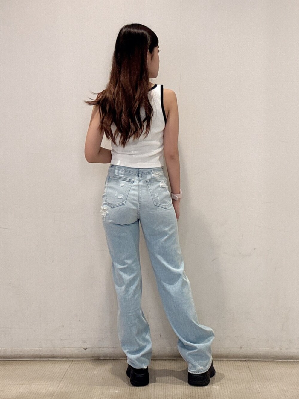 ブラック系のスニーカー、ホワイト系のタンクトップ、ブルー系のデニムパンツを着用したレディースの春コーディネートの3枚目の写真