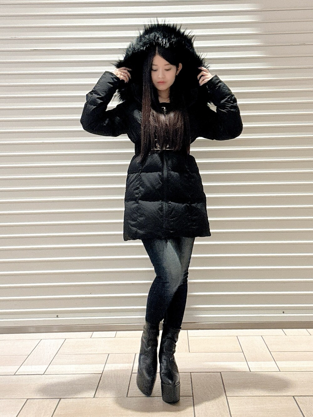 ブラック系のニット/セーター、ブラック系のダウンジャケット/コート、ブルー系のデニムパンツを着用したレディースの秋コーディネートの2枚目の写真