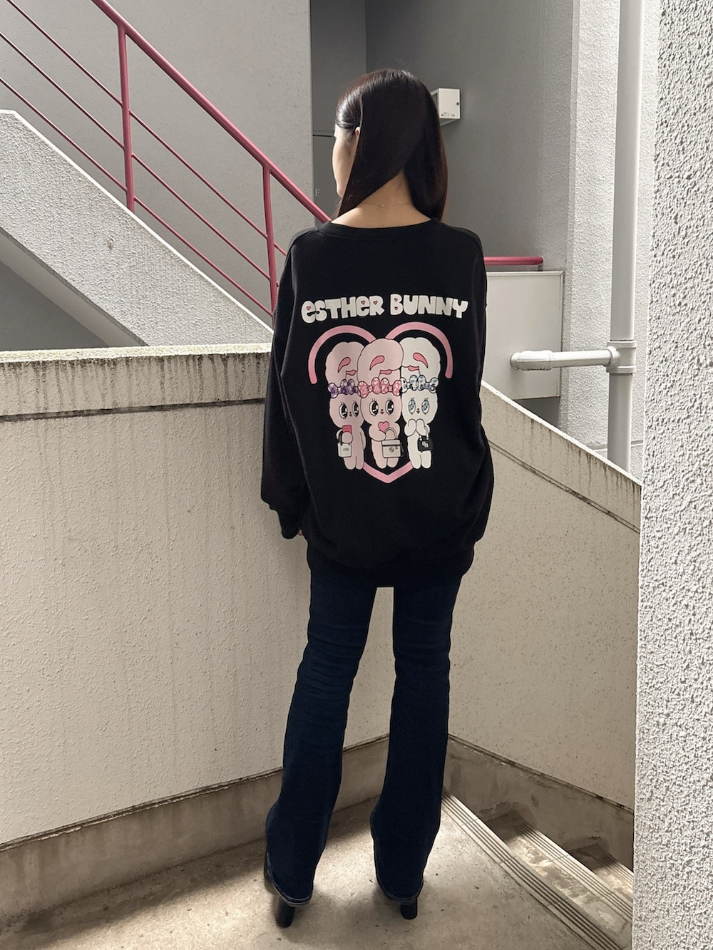 ブラック系のスウェット、ブルー系のデニムパンツ、ブラック系のブーツを着用したレディースの秋コーディネートの3枚目の写真