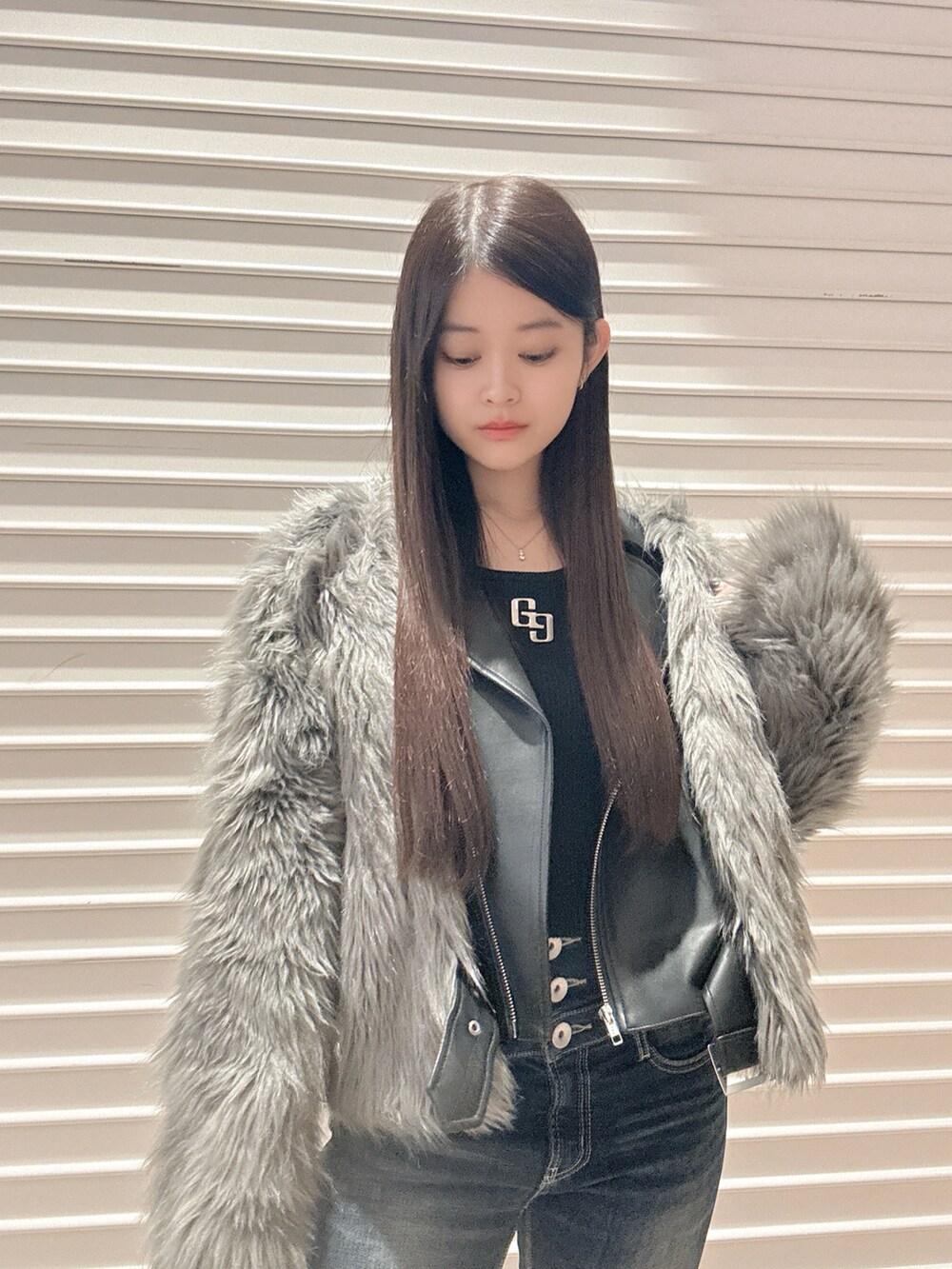 ブラック系のニット/セーター、グレー系のライダースジャケット、ブルー系のデニムパンツを着用したレディースの秋コーディネートの5枚目の写真