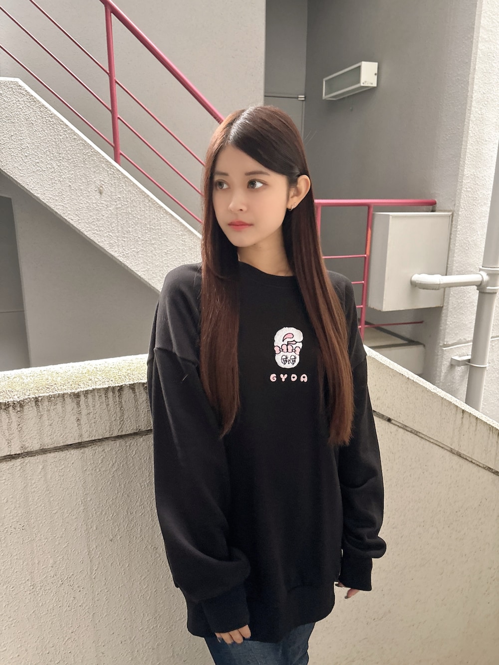 ブラック系のスウェット、ブルー系のデニムパンツ、ブラック系のブーツを着用したレディースの秋コーディネートの4枚目の写真