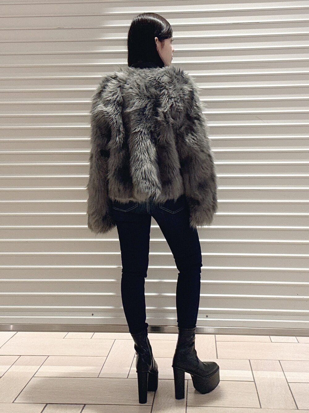 ブラック系のニット/セーター、グレー系のライダースジャケット、ブルー系のデニムパンツを着用したレディースの秋コーディネートの4枚目の写真