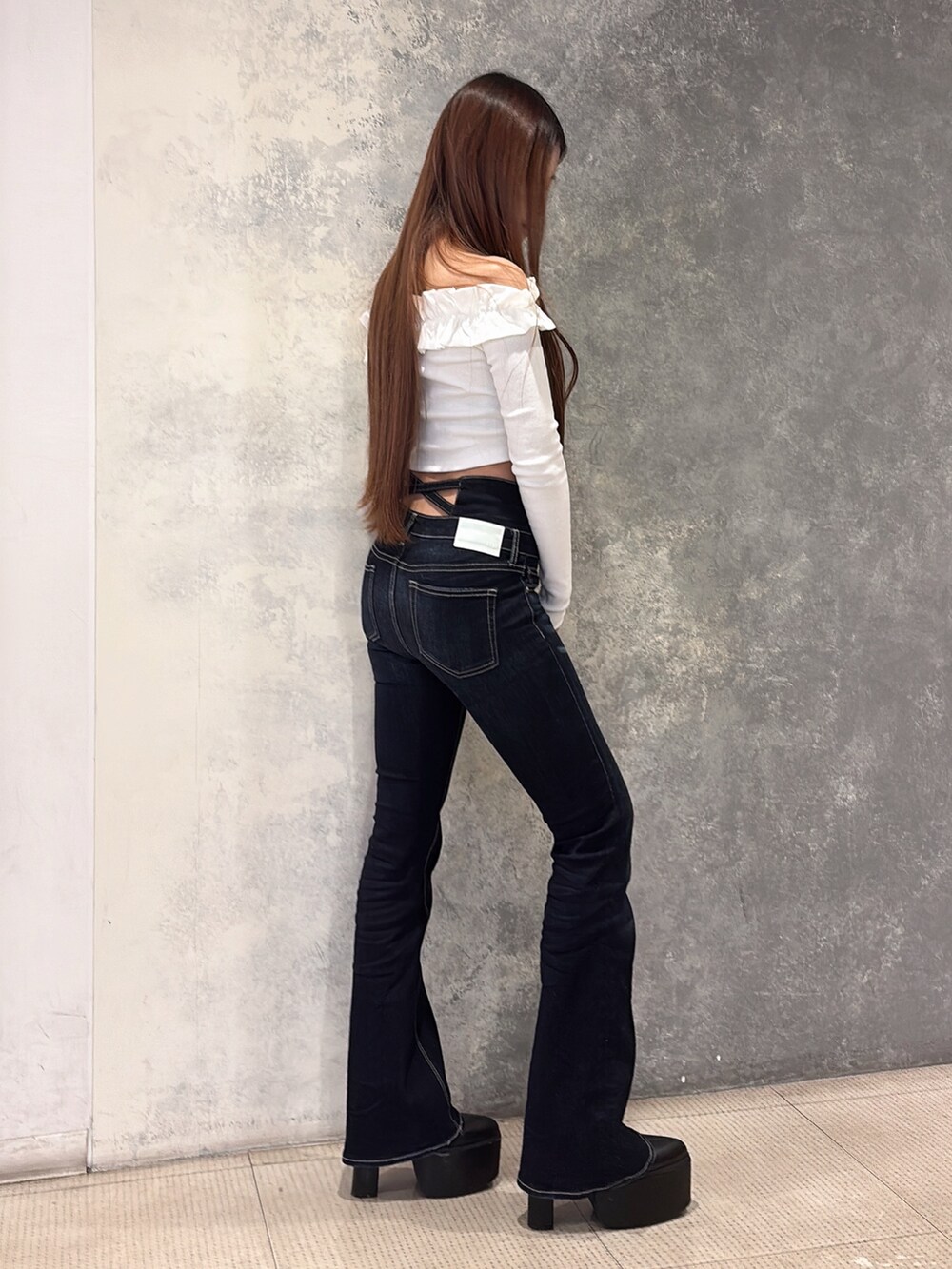 ホワイト系のTシャツ/カットソー、ブルー系のデニムパンツ、ブラック系のブーツを着用したレディースの冬コーディネートの2枚目の写真