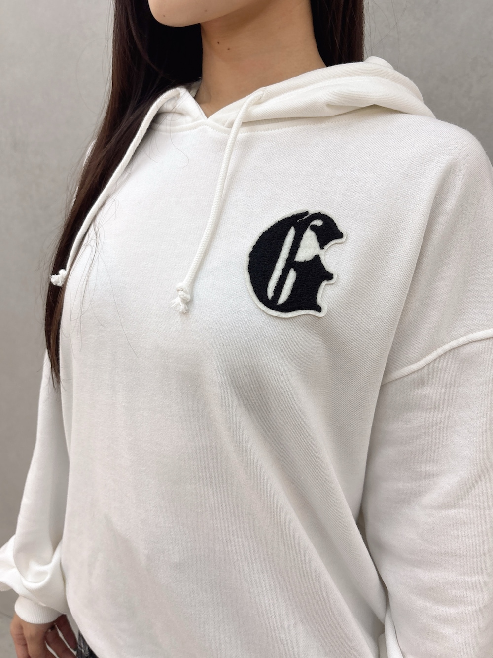 ホワイト系のパーカー、ブラック系のスカート、ブラック系のブーツを着用したレディースの秋コーディネートの6枚目の写真