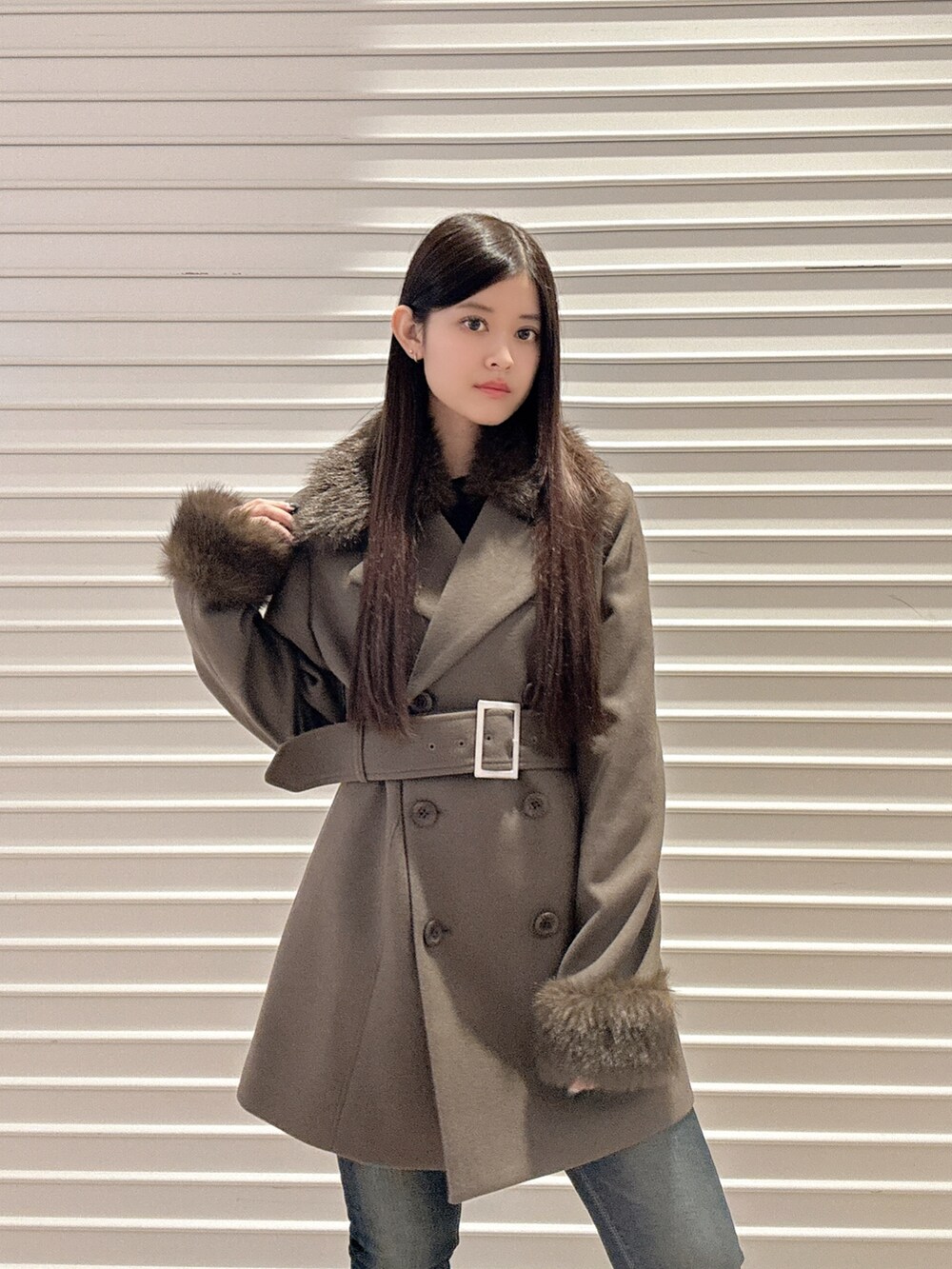 ブラック系のニット/セーター、ブラウン系のチェスターコート、ブルー系のデニムパンツを着用したレディースの秋コーディネートの5枚目の写真