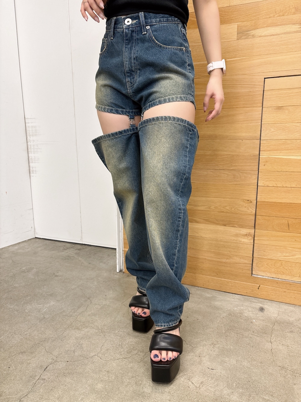 ブラック系のニット/セーター、ブルー系のデニムパンツ、ブラック系のサンダルを着用したレディースの夏コーディネートの6枚目の写真