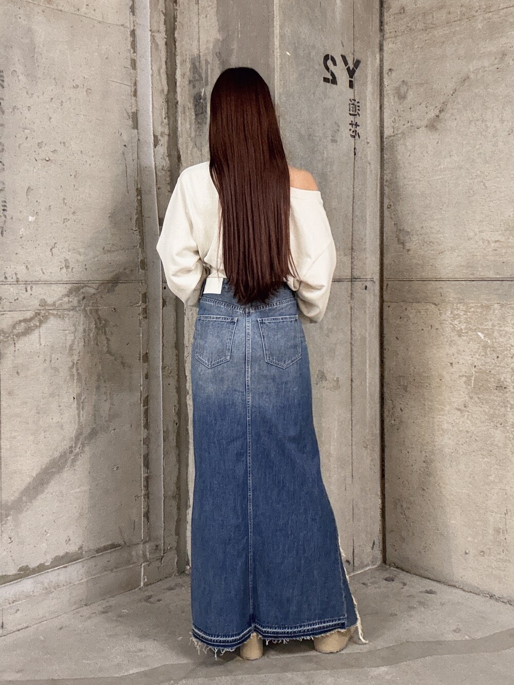 ホワイト系のスウェット、ブルー系のデニムスカート、ベージュ系のブーツを着用したレディースの秋コーディネートの3枚目の写真