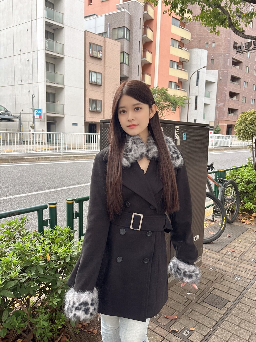 ブラック系のTシャツ/カットソー、ブラック系のチェスターコート、ブルー系のデニムパンツを着用したレディースの秋コーディネートの4枚目の写真