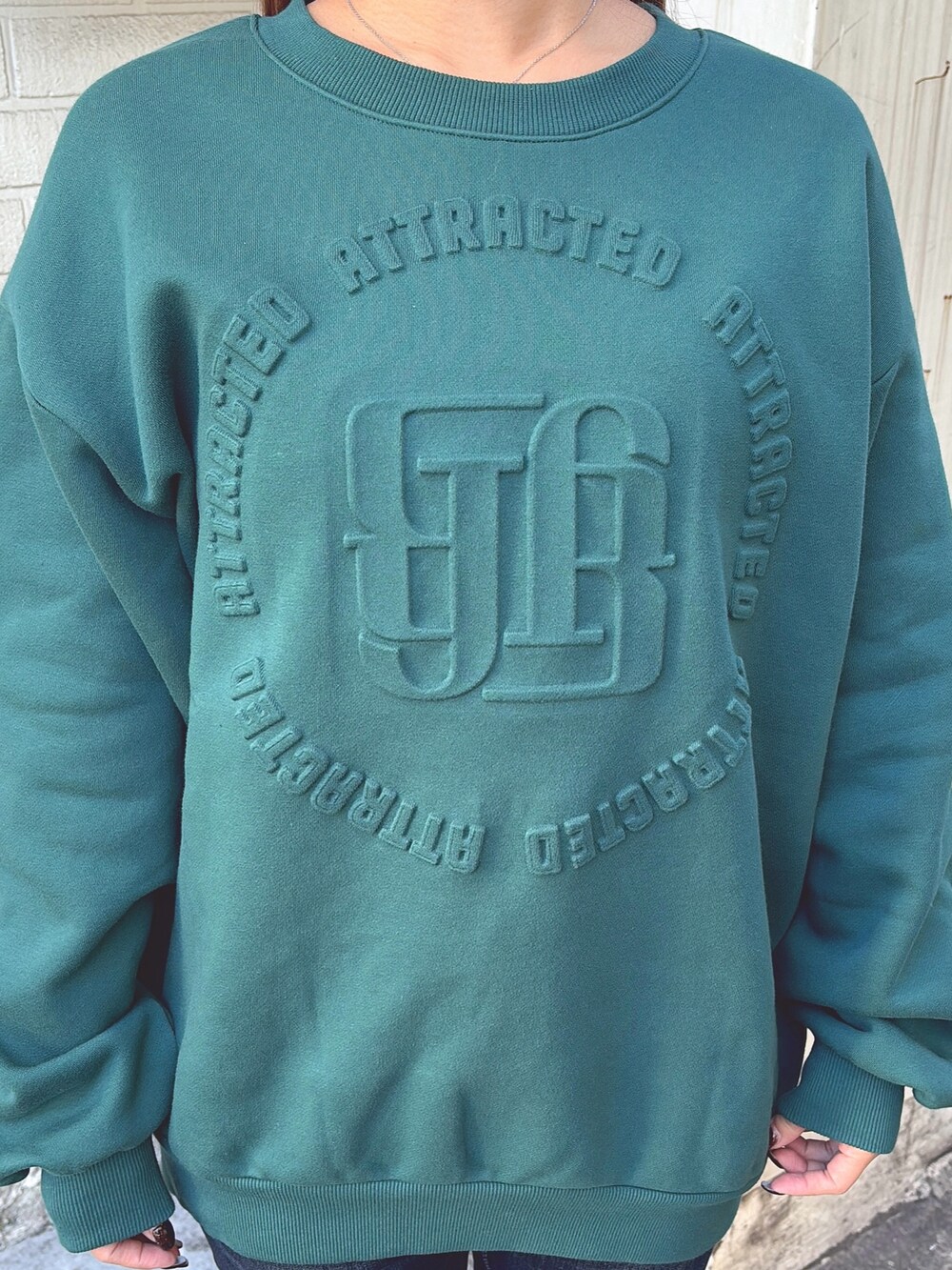 グリーン系のスウェット、ブルー系のデニムパンツ、ブラック系のブーツを着用したレディースの冬コーディネートの4枚目の写真