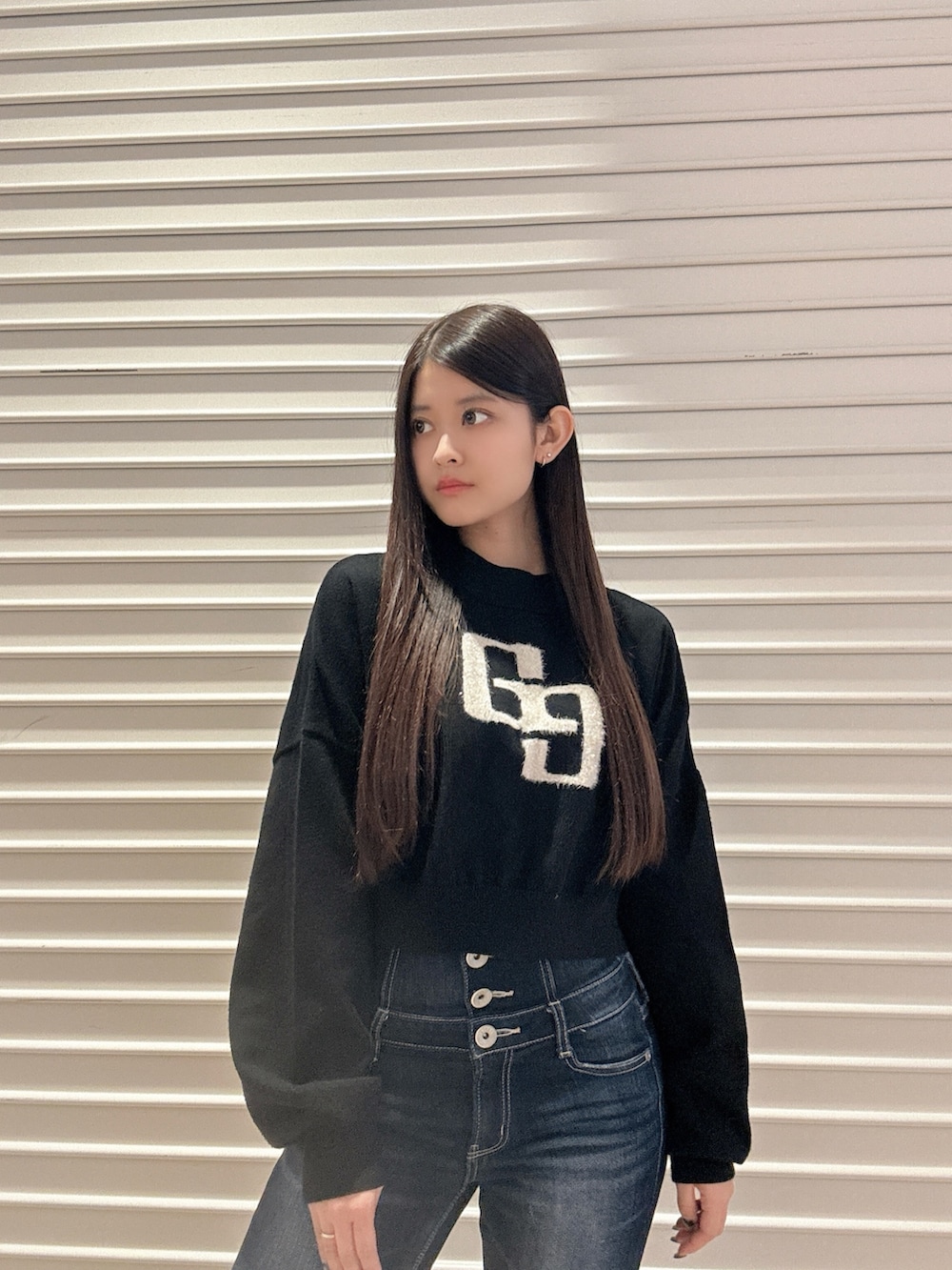 ブラック系のニット/セーター、ブルー系のデニムパンツ、ブラック系のブーツを着用したレディースの秋コーディネートの5枚目の写真